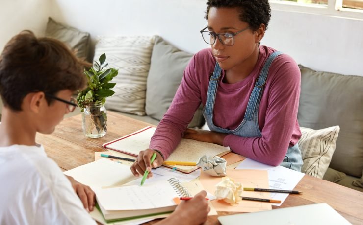 Tutoring, education and encouragement concept. Serious black female tutor conducts geometry class with traninee who has individual tutoring lesson, work one to one, prepare for final examination.